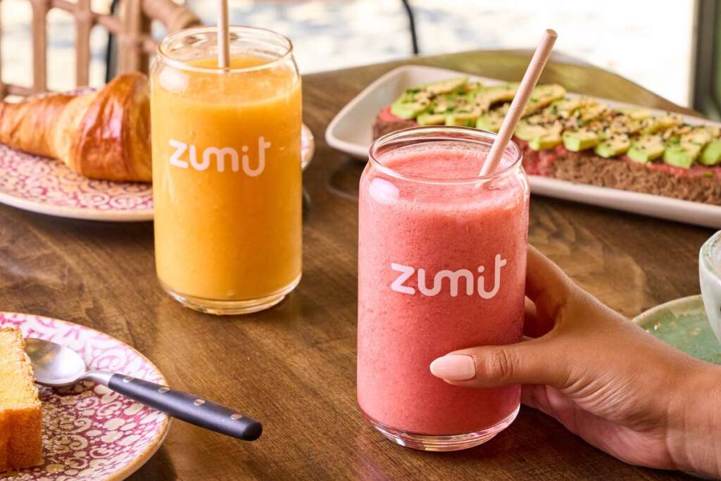 Smoothie manga, ananás e papaia naturais numa mesa de madeira com pequeno-almoço